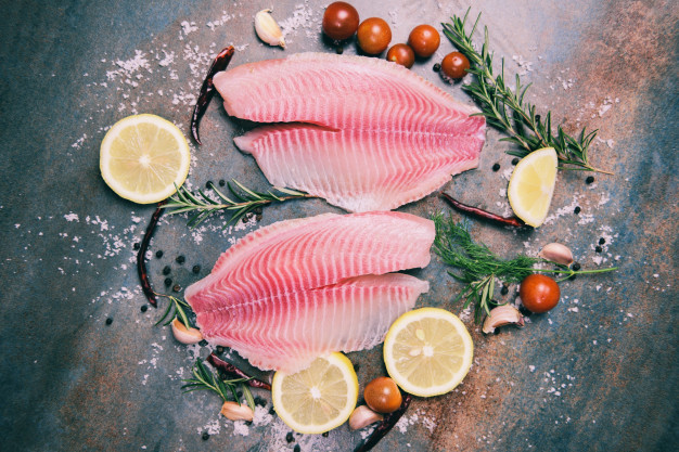 fresh-fish-fillet-sliced-steak-salad-with-herbs-spices-rosemary-tomato-lemon-raw-tilapia-fillet-fish-salt-dark-stone-background-ingredients-cooking-food_73523-3271